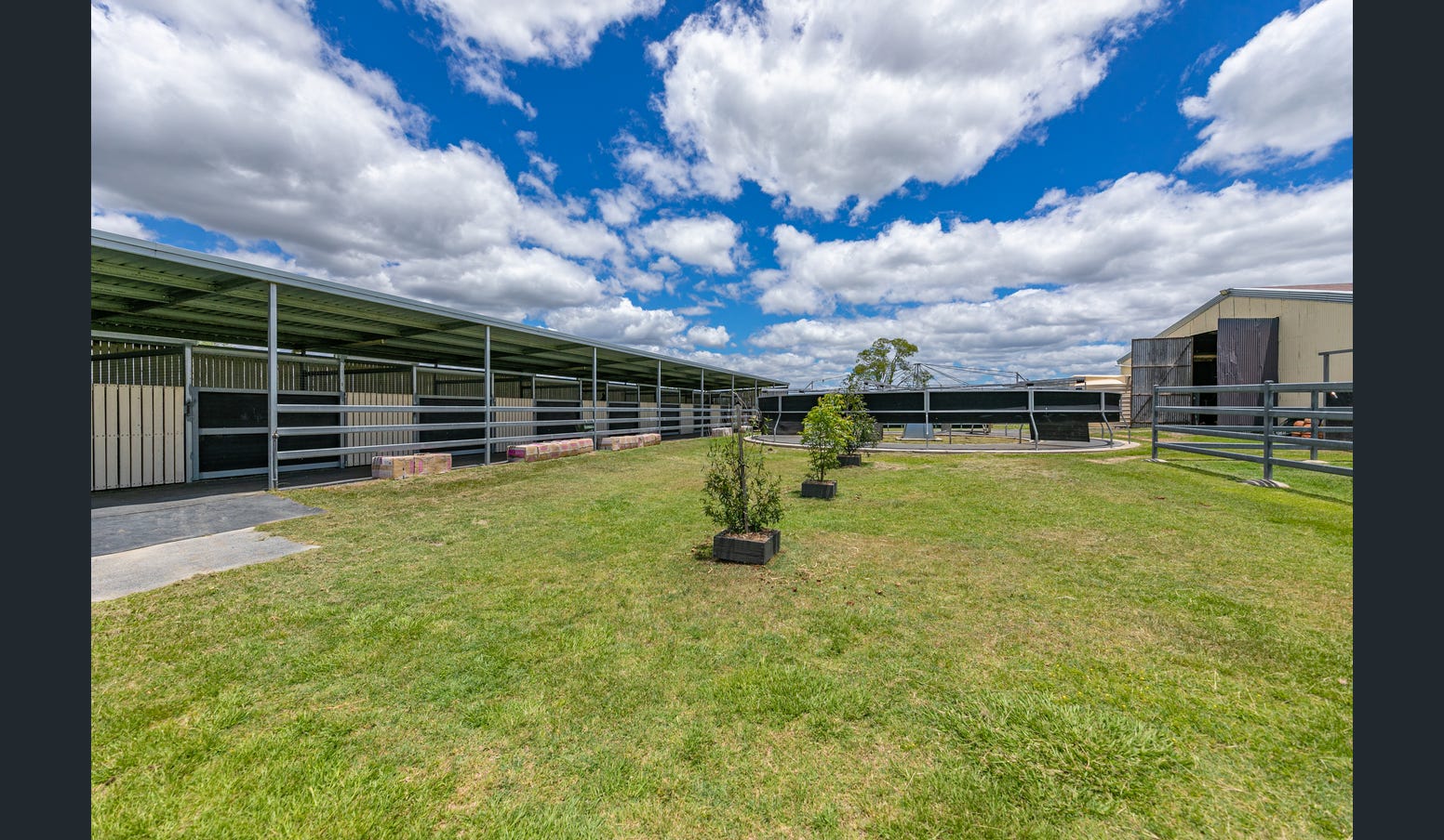 Stables and round yard under a wide cloudy sky